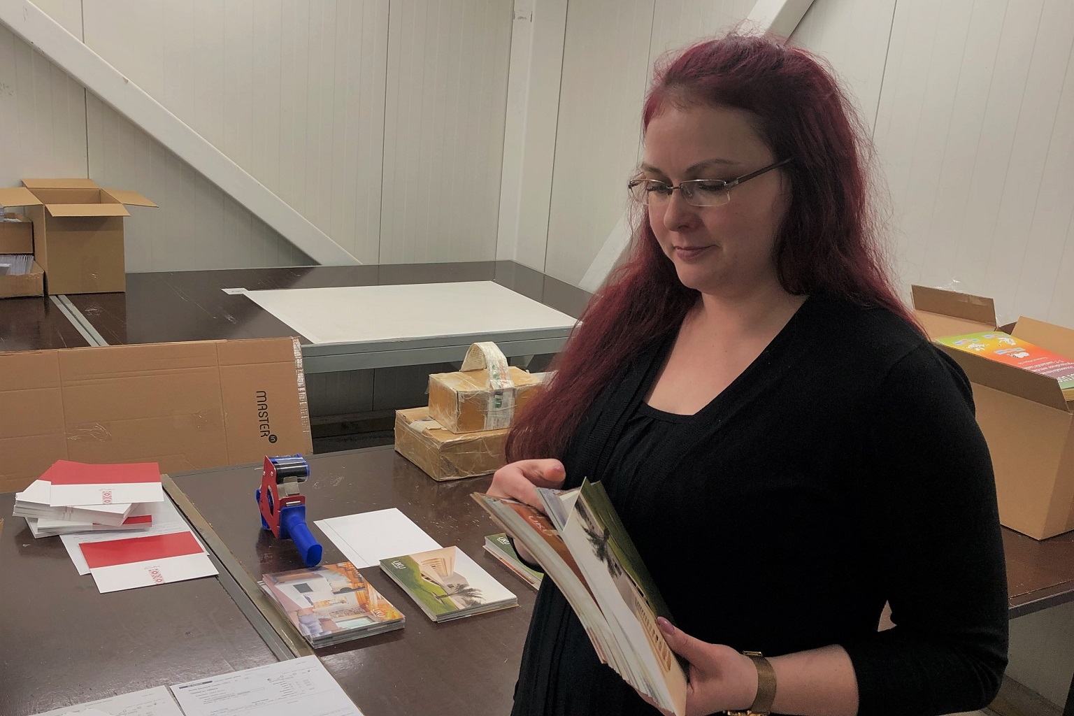 järeltöötleja-pakendaja kerli oma töölaua taga trükiseid kontrollimas